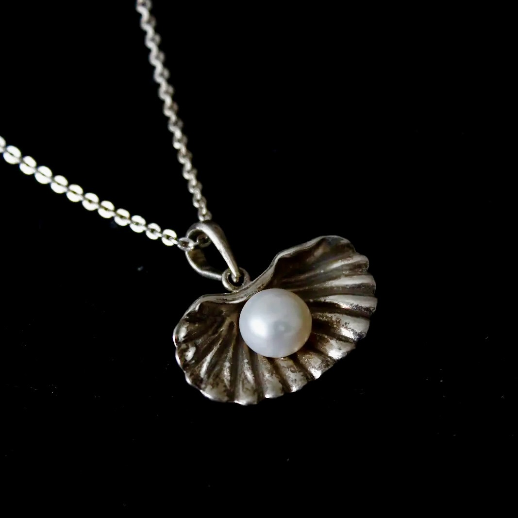 This silver seashell locket holds a pearl with a gentle reminder that softness and strength live tog - View 1